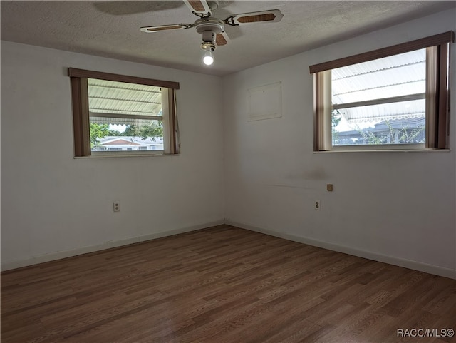 spare room featuring plenty of natural light, dark hardwood / wood-style floors, a textured ceiling, and ceiling fan