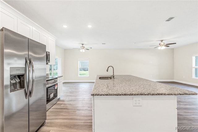 kitchen with white cabinetry, sink, stainless steel appliances, and light hardwood / wood-style floors