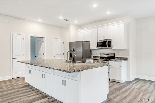 kitchen featuring white cabinetry, a center island with sink, stainless steel appliances, and light hardwood / wood-style floors