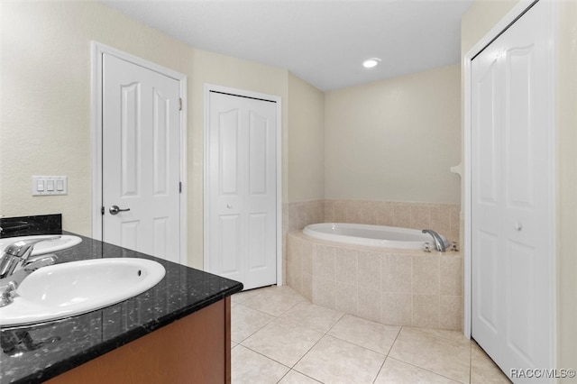 bathroom with tile patterned flooring, vanity, and a relaxing tiled tub