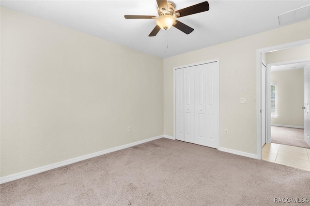 unfurnished bedroom featuring ceiling fan, a closet, and light carpet