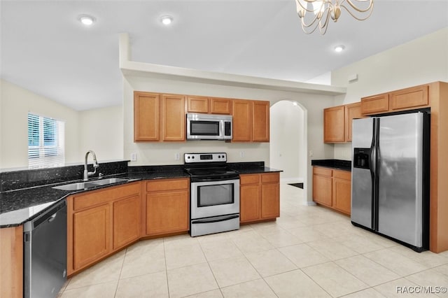 kitchen with dark stone counters, sink, light tile patterned floors, a notable chandelier, and stainless steel appliances