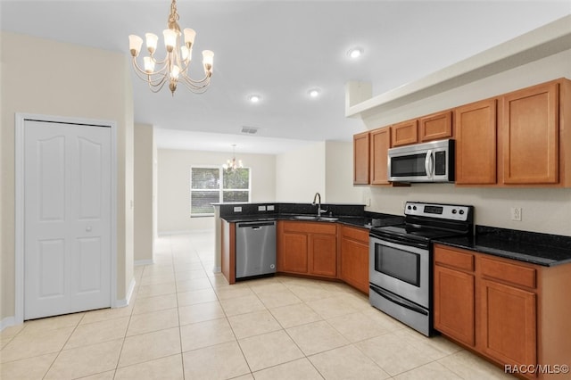 kitchen with sink, appliances with stainless steel finishes, decorative light fixtures, kitchen peninsula, and a chandelier