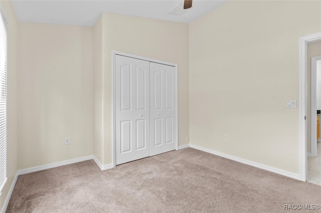 unfurnished bedroom featuring light colored carpet, a closet, and ceiling fan