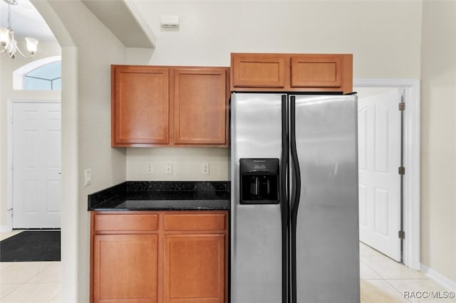 kitchen featuring pendant lighting, dark stone counters, stainless steel fridge with ice dispenser, and light tile patterned floors