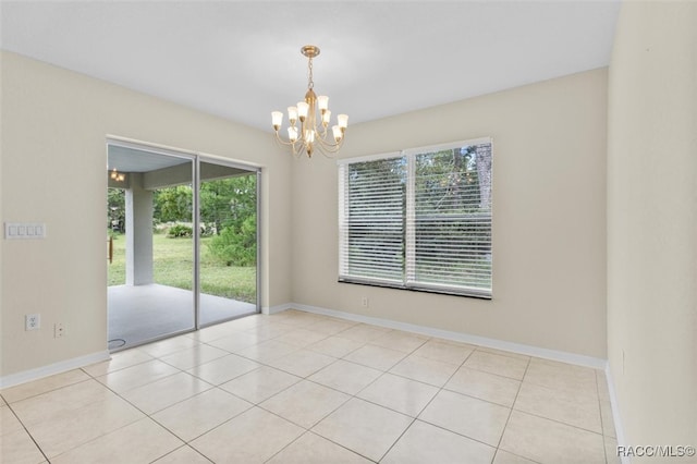 tiled empty room with plenty of natural light and a chandelier