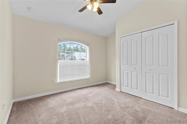 unfurnished bedroom featuring lofted ceiling, light colored carpet, ceiling fan, and a closet