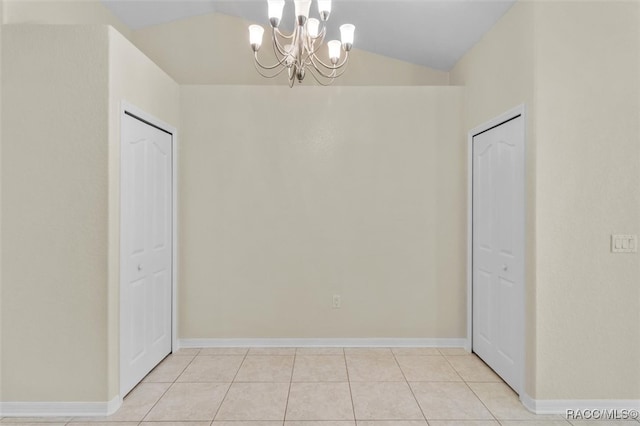 spare room featuring an inviting chandelier, vaulted ceiling, and light tile patterned floors