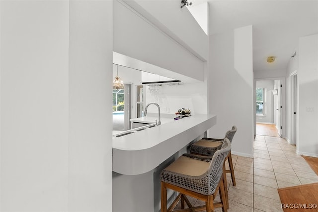 kitchen featuring plenty of natural light, light tile patterned floors, sink, and kitchen peninsula