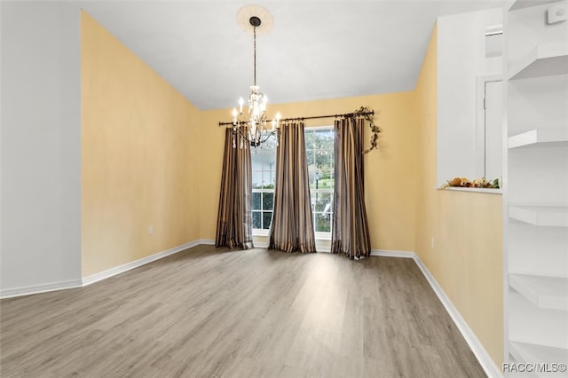 spare room featuring light hardwood / wood-style flooring and a notable chandelier