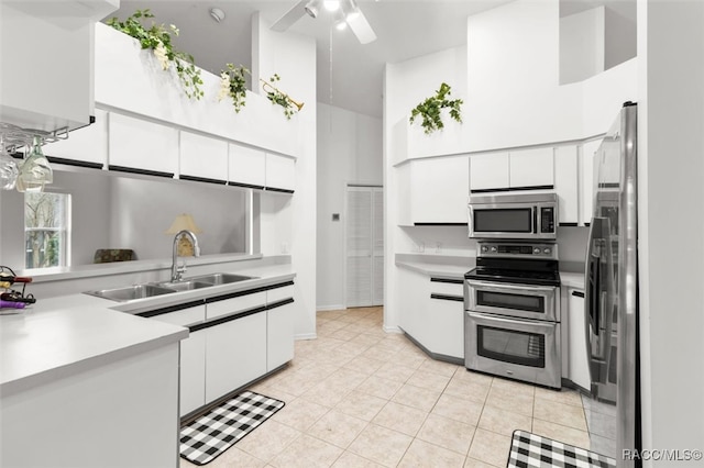 kitchen with white cabinets, appliances with stainless steel finishes, a high ceiling, and sink