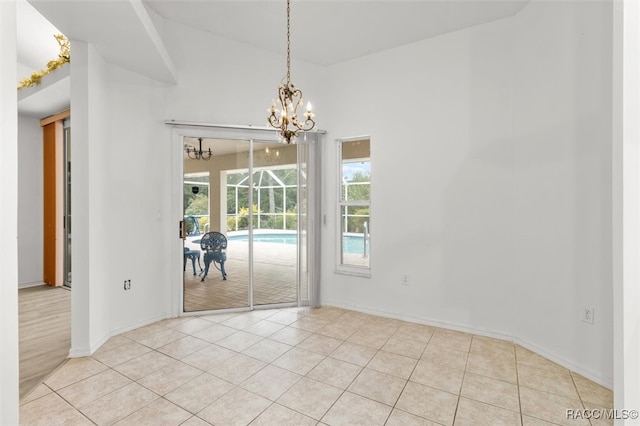 empty room with a notable chandelier and light tile patterned floors