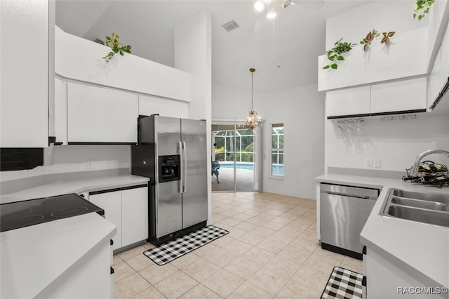 kitchen featuring stainless steel appliances, sink, decorative light fixtures, high vaulted ceiling, and white cabinetry