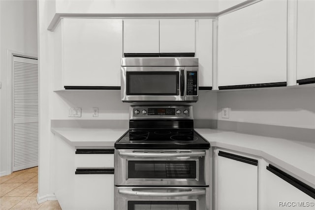 kitchen featuring light tile patterned floors, stainless steel appliances, and white cabinetry