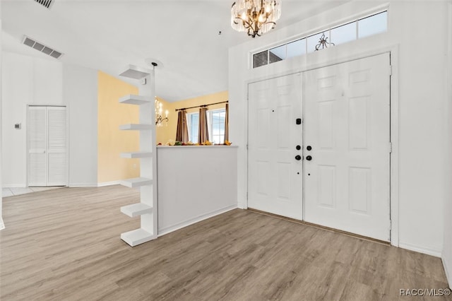 entrance foyer with wood-type flooring, lofted ceiling, and a notable chandelier