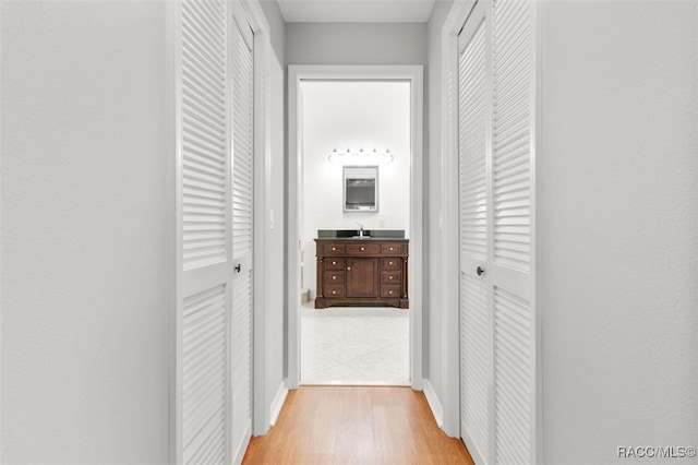 corridor with light hardwood / wood-style flooring and sink