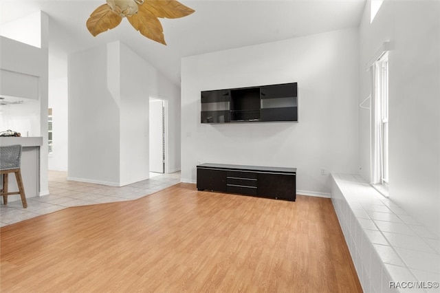 unfurnished living room featuring ceiling fan, hardwood / wood-style floors, and a towering ceiling