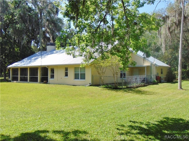 rear view of house with a lawn and a sunroom