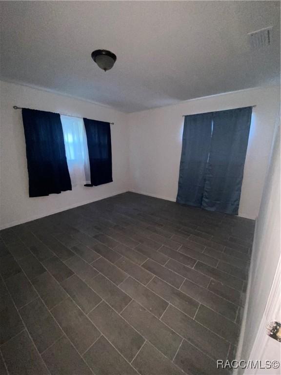 spare room with a textured ceiling and dark wood-type flooring