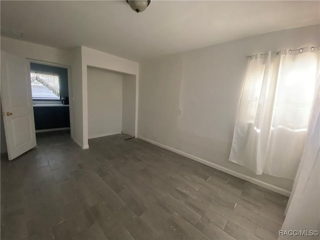 unfurnished bedroom featuring a closet and dark wood-type flooring