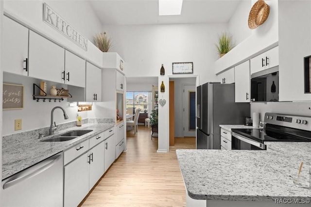 6150 N Whispering Oak Loop, Beverly Hills, FL 34465 - kitchen featuring stainless steel appliances, a sink, light wood-style floors, white cabinetry, and a high ceiling