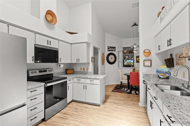 6150 N Whispering Oak Loop, Beverly Hills, FL 34465 - kitchen featuring stainless steel appliances, a sink, white cabinets, light wood-type flooring, and a high ceiling