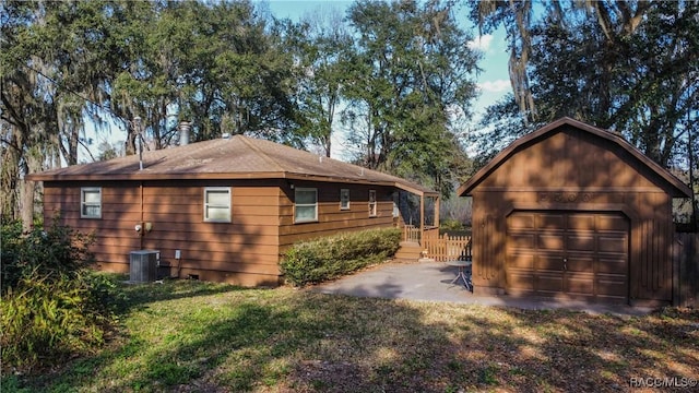 view of side of home with cooling unit, a garage, an outdoor structure, and a lawn