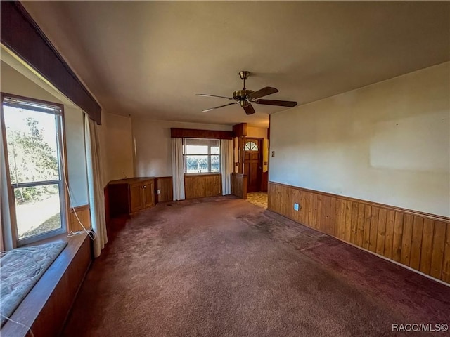 spare room with carpet, ceiling fan, and wood walls