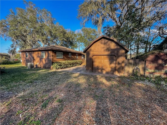 exterior space featuring an outbuilding, a garage, a lawn, and central air condition unit