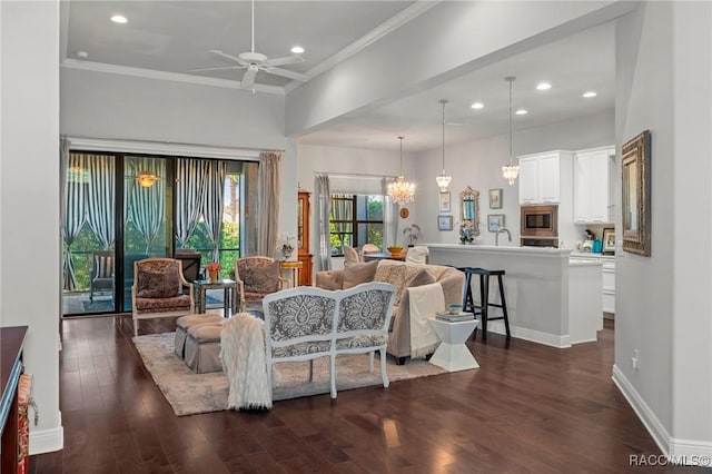 living room featuring recessed lighting, ceiling fan with notable chandelier, dark wood-type flooring, baseboards, and ornamental molding