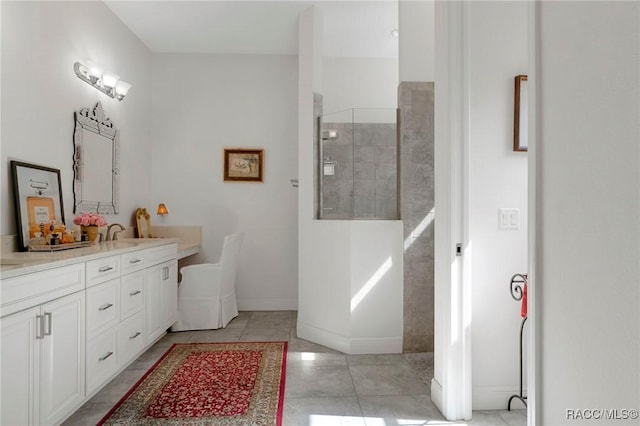 full bath featuring tile patterned floors, vanity, baseboards, and walk in shower