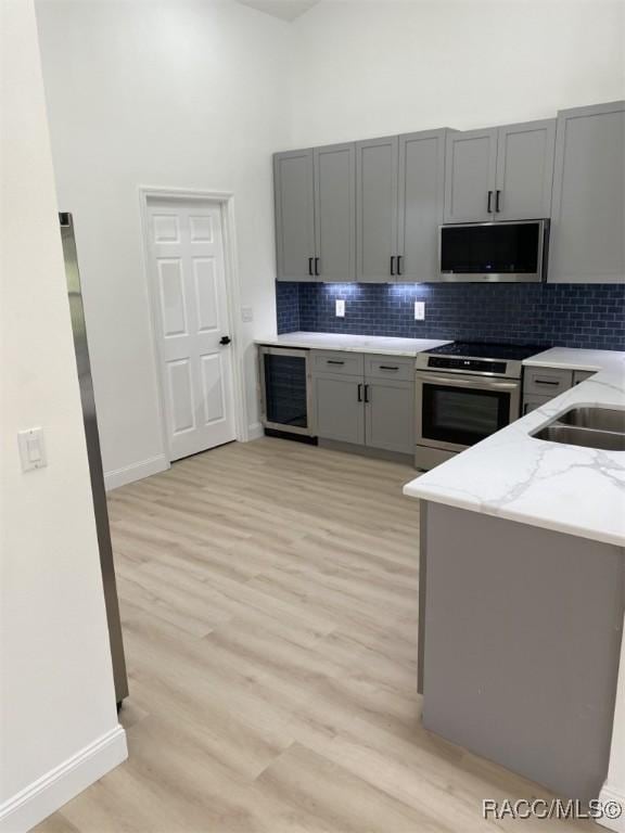 259 N Cherry Pop Dr, Inverness, FL 34453 - kitchen with stainless steel appliances, gray cabinetry, a high ceiling, and light wood finished floors