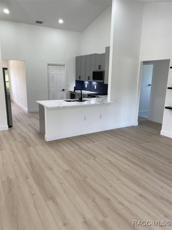 259 N Cherry Pop Dr, Inverness, FL 34453 - kitchen with high vaulted ceiling, stainless steel microwave, a sink, gray cabinetry, and baseboards