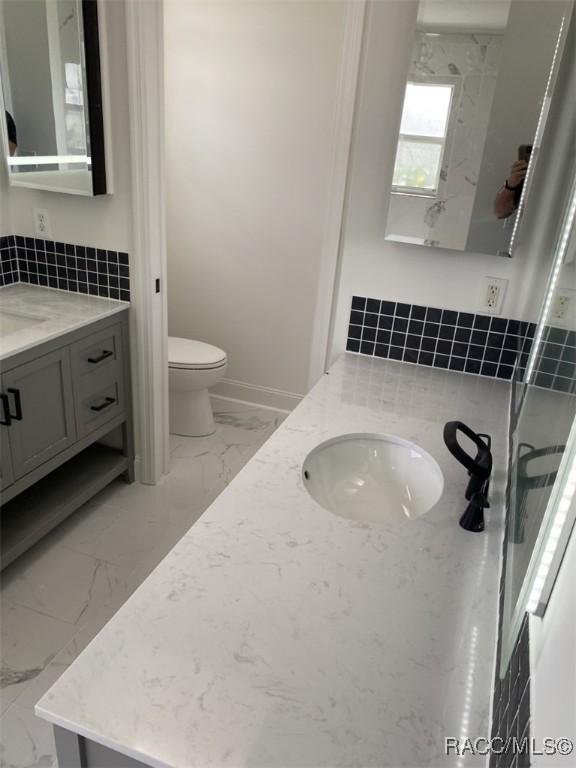 259 N Cherry Pop Dr, Inverness, FL 34453 - bathroom featuring marble finish floors, vanity, toilet, and baseboards