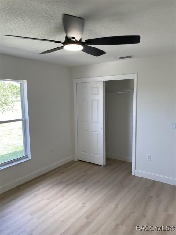 259 N Cherry Pop Dr, Inverness, FL 34453 - unfurnished bedroom with light wood-type flooring, a closet, baseboards, and ceiling fan