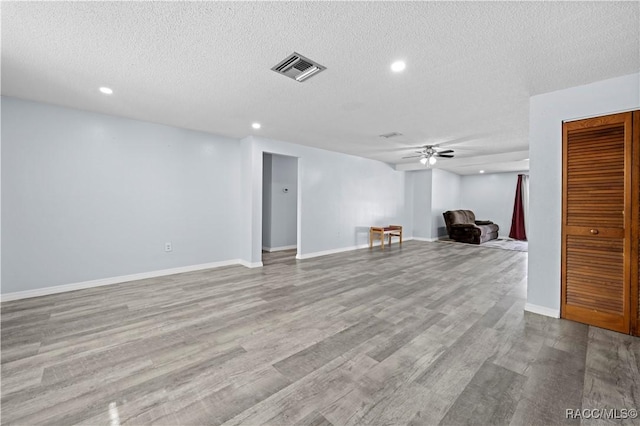 unfurnished living room featuring ceiling fan, a textured ceiling, and light hardwood / wood-style floors