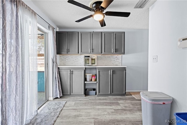 interior space with a textured ceiling, ceiling fan, and light hardwood / wood-style flooring