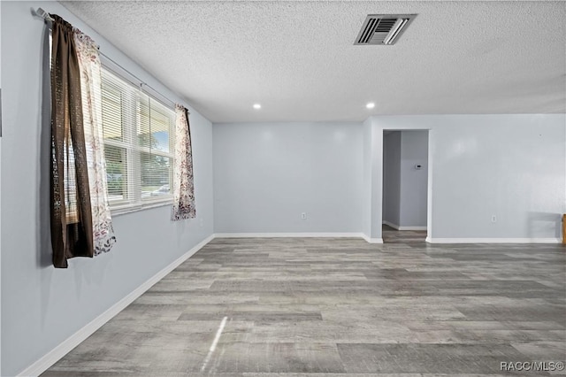 empty room with a textured ceiling and light wood-type flooring