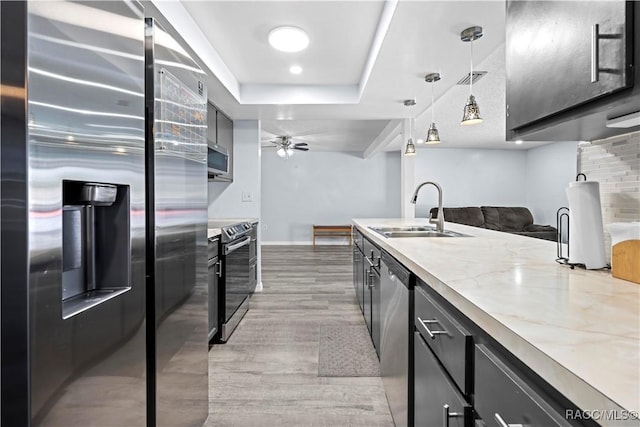 kitchen with ceiling fan, pendant lighting, sink, stainless steel appliances, and light stone counters