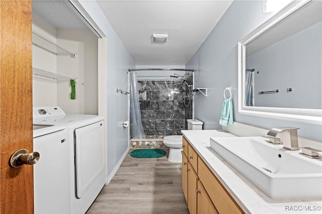 bathroom with toilet, hardwood / wood-style floors, walk in shower, washing machine and dryer, and vanity