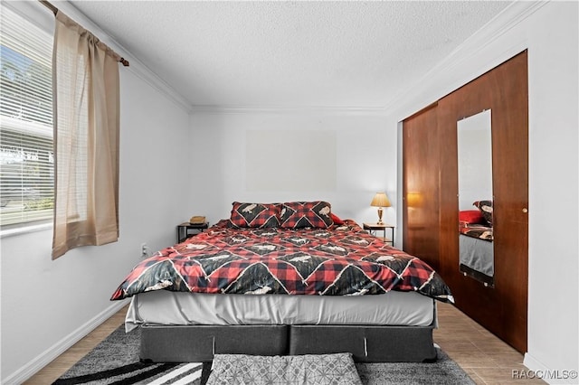 bedroom featuring light hardwood / wood-style floors, a textured ceiling, and crown molding