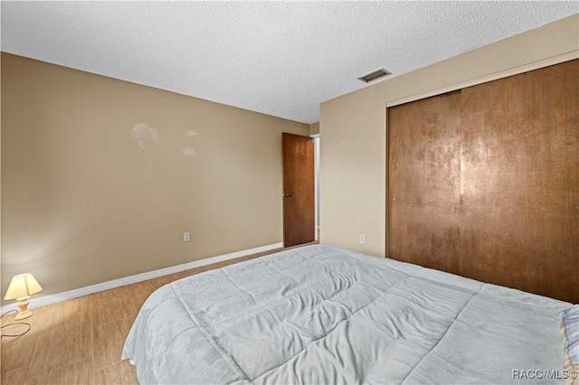 bedroom with a closet, a textured ceiling, and wood-type flooring