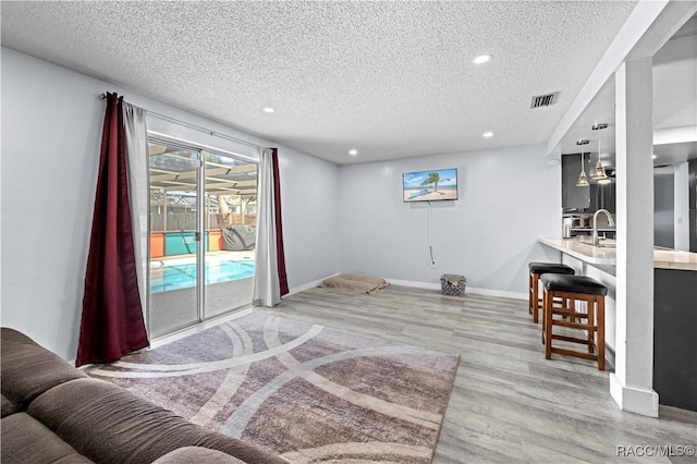 interior space with light hardwood / wood-style floors, sink, a textured ceiling, and access to outside