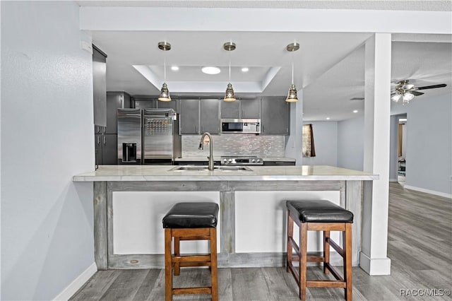 kitchen with stainless steel appliances, sink, hanging light fixtures, kitchen peninsula, and a breakfast bar