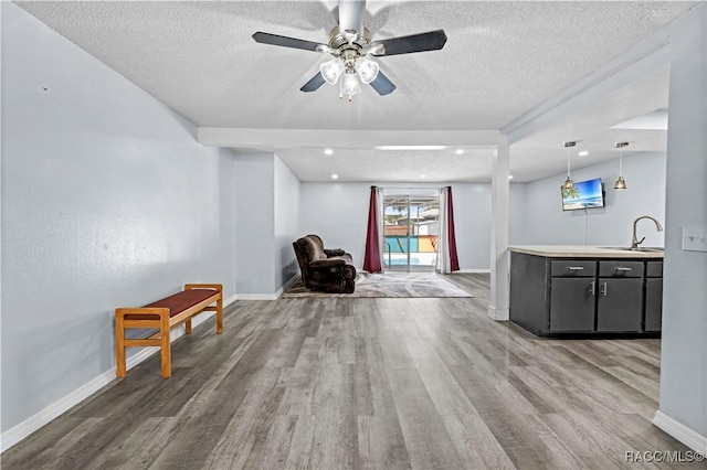 unfurnished room featuring ceiling fan, sink, hardwood / wood-style floors, and a textured ceiling