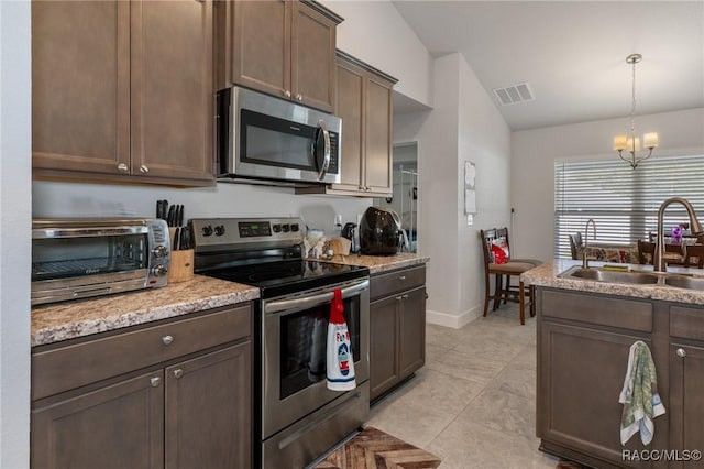 kitchen with pendant lighting, stainless steel appliances, visible vents, vaulted ceiling, and a sink