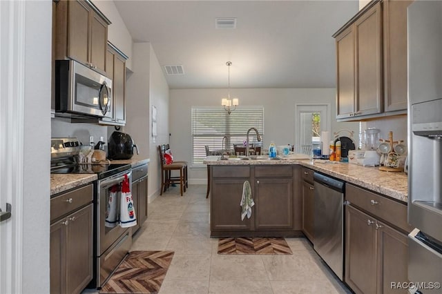 kitchen with hanging light fixtures, appliances with stainless steel finishes, light tile patterned flooring, a sink, and a peninsula