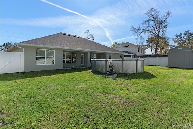 rear view of house featuring an outbuilding, a storage unit, a lawn, and fence