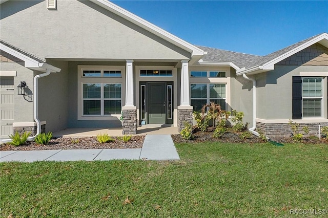 doorway to property with a porch, stone siding, a lawn, and stucco siding