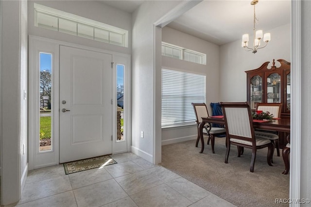 entryway with light carpet, light tile patterned floors, plenty of natural light, and a chandelier